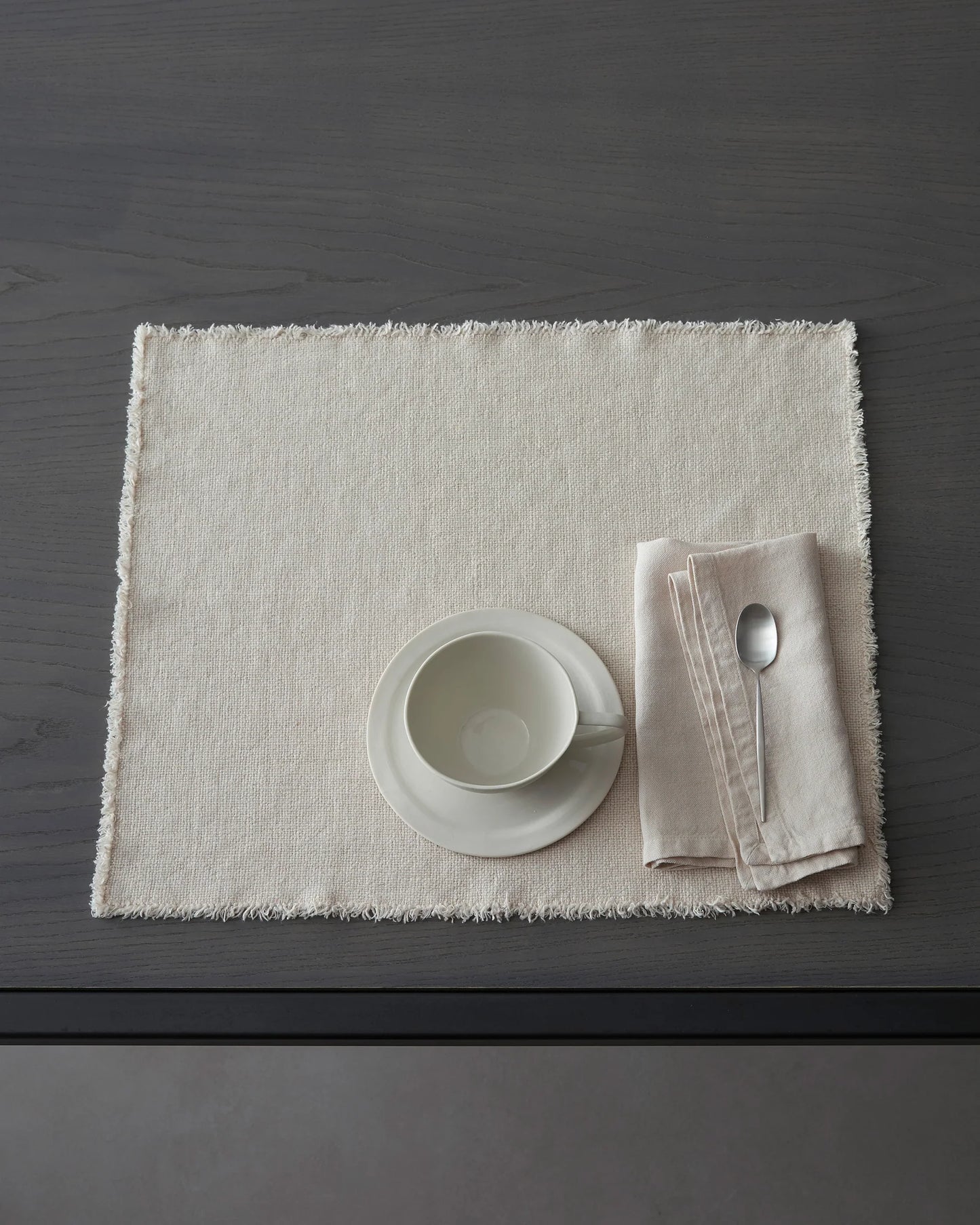 Table setting with a white bowl, napkin, and spoon on Maya linen placemat