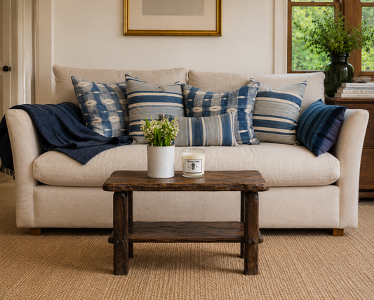 Beige sofa with blue and gray striped pillows, a wooden coffee table with decor items, and a framed picture on the wall.
