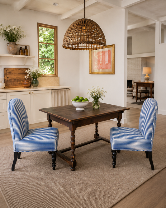 Dining room with wooden table and blue chairs, wicker pendant light, and decorative elements.