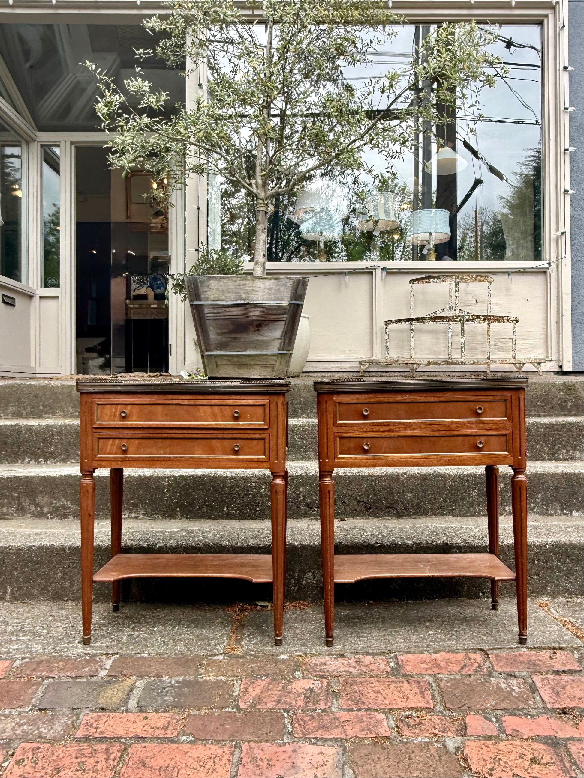 Two wooden side tables with marble tops on a patio.