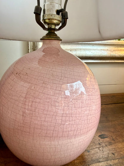 Pink ceramic lamp with a cracked glaze finish on a wooden surface.