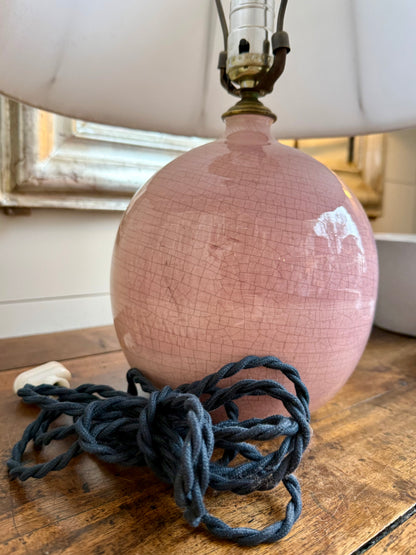 Pink ceramic lamp with white lampshade on a wooden surface