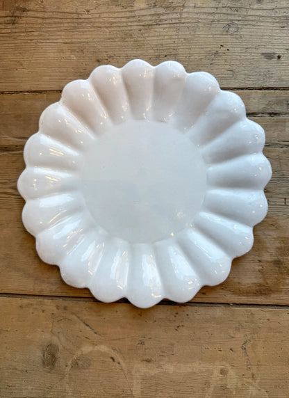 White scalloped-edge dish on a wooden surface