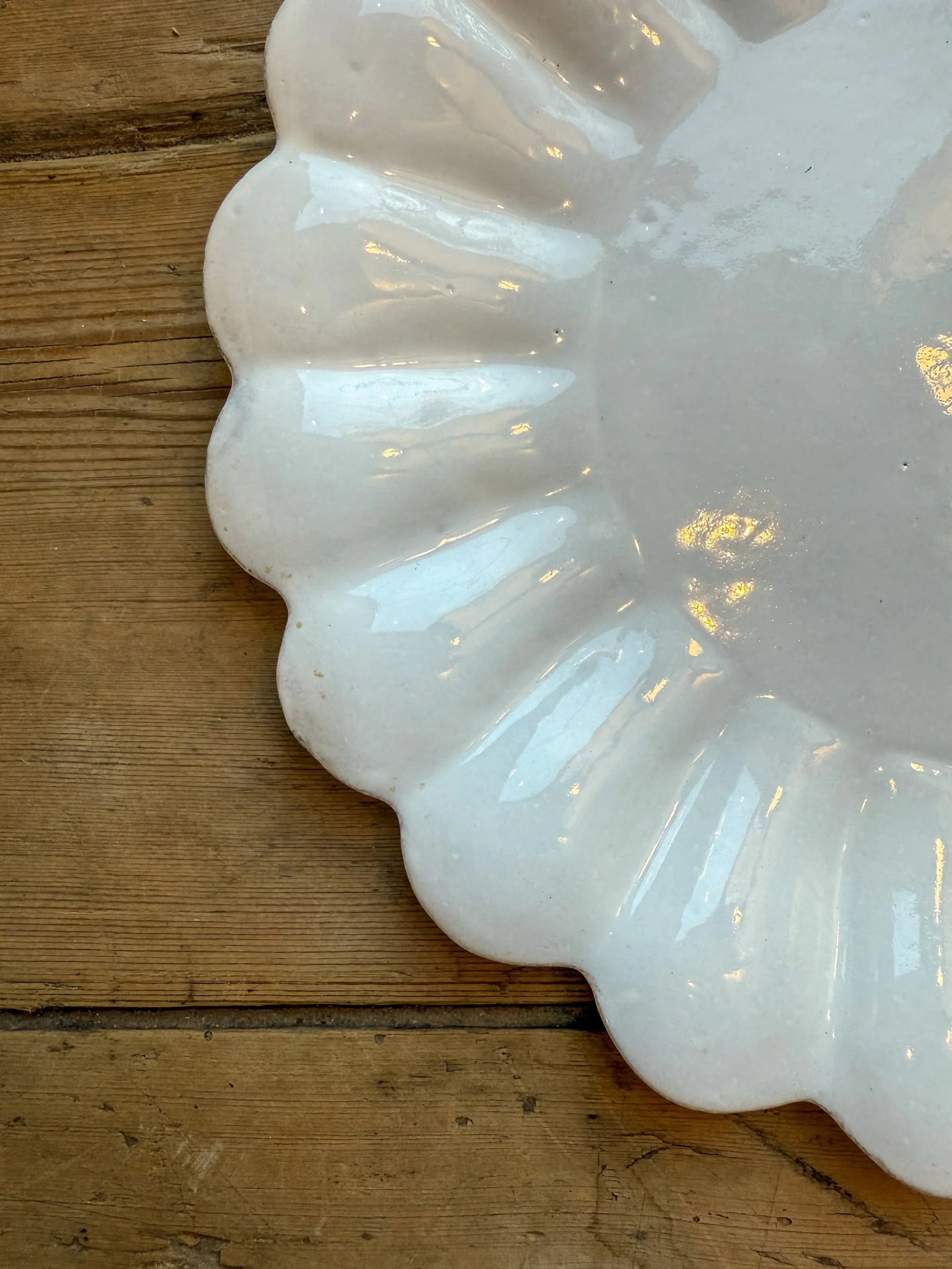 White ceramic plate with scalloped edge on a wooden surface