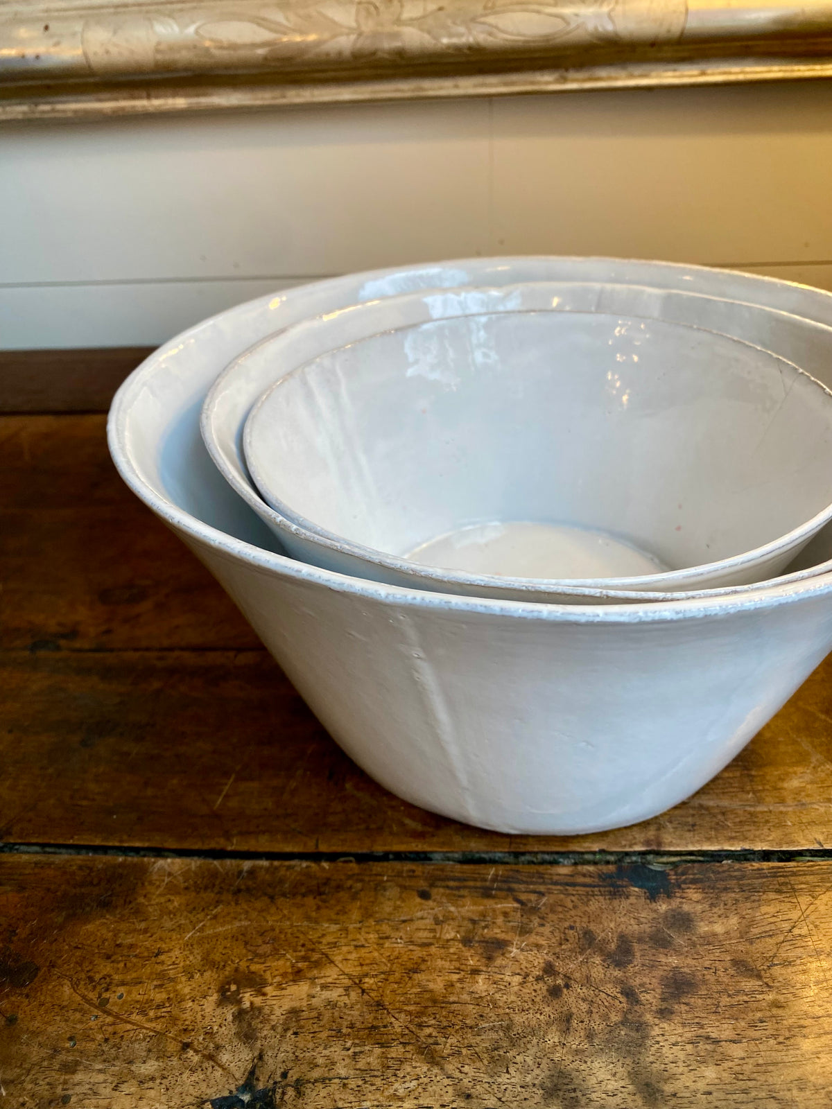Stack of white Astier ceramic bowls on a wooden surface