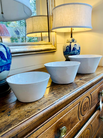 A row of three white Astier ceramic bowls on a wooden surface