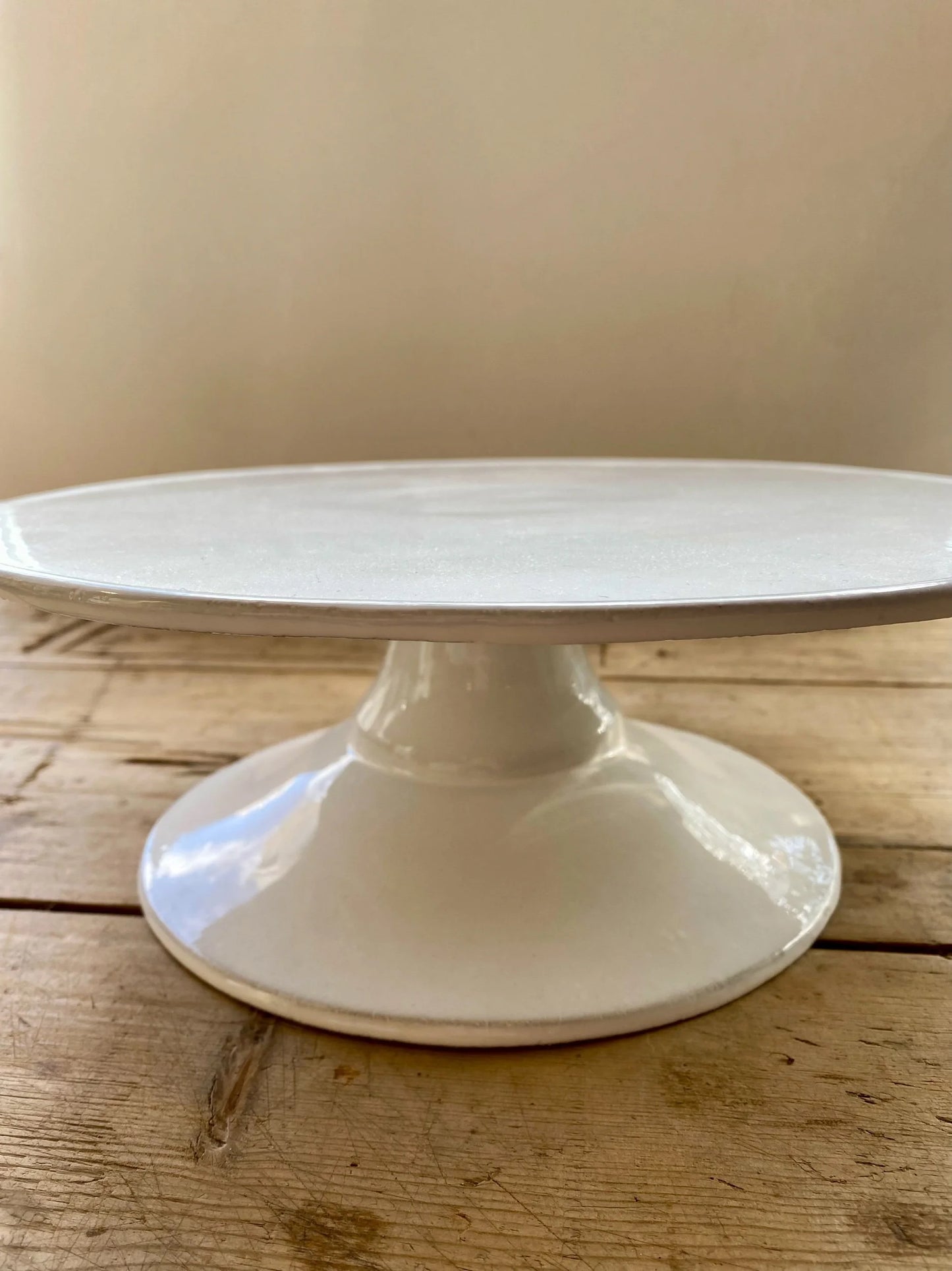 White cake stand on a wooden surface with a beige background