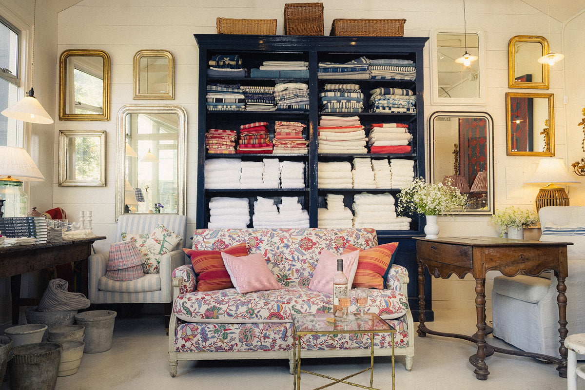 Living room with floral sofa, bookshelf, and decorative mirrors.