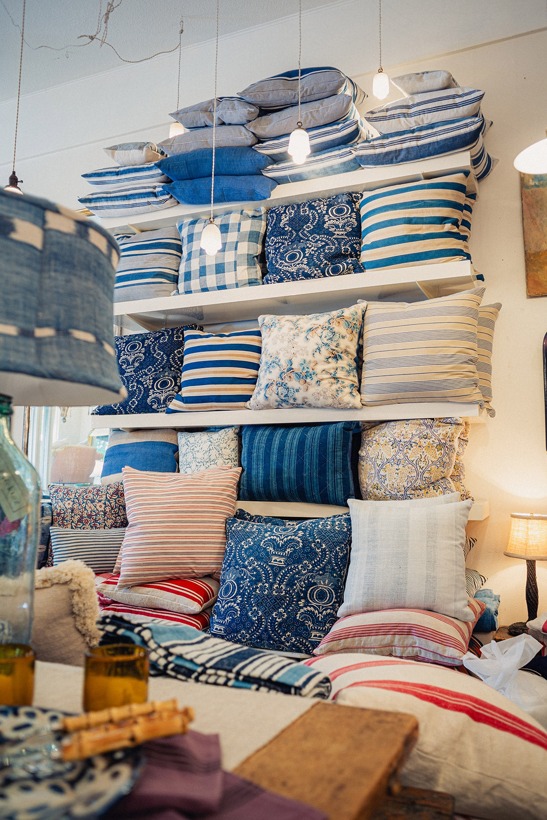 Display of various pillows on shelves with a focus on blue and patterned designs.