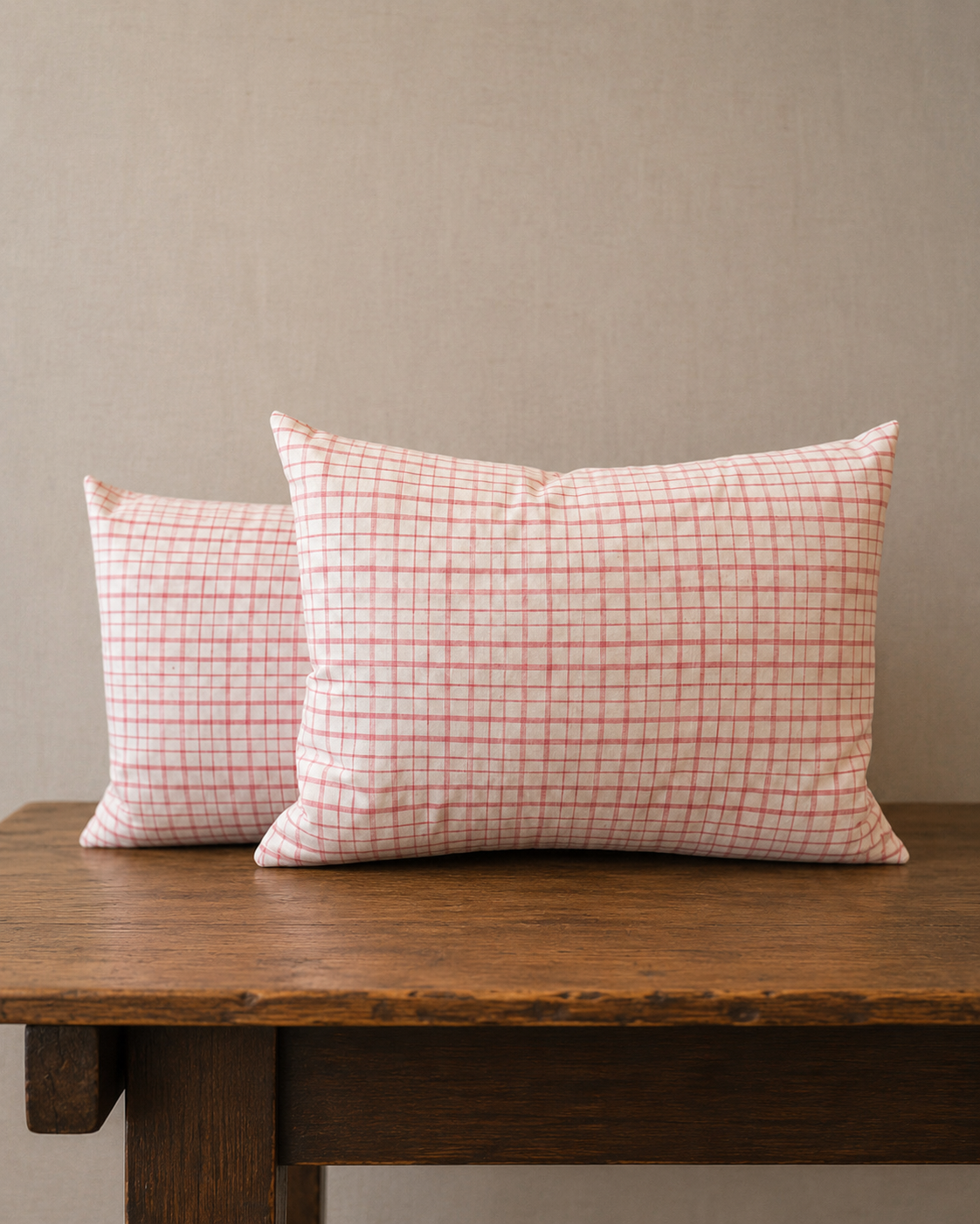 Two checkered pillows on a wooden table against a beige wall