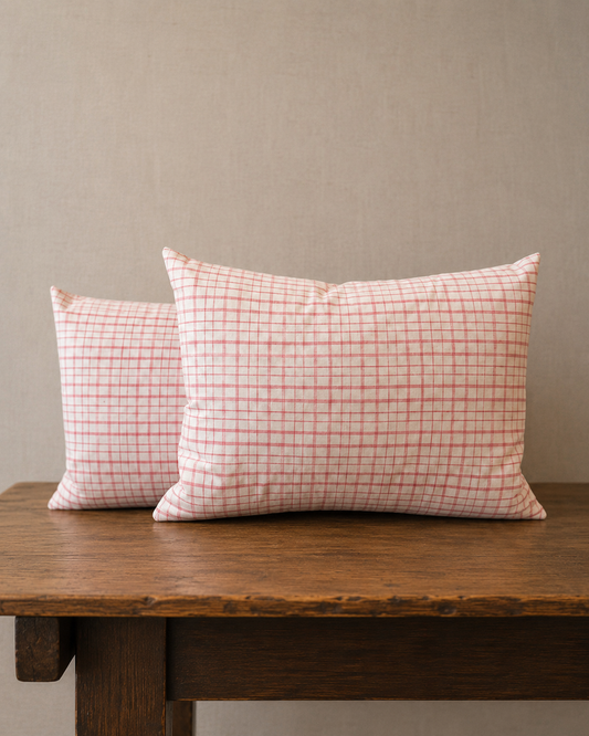 Two checkered pillows on a wooden table against a beige wall