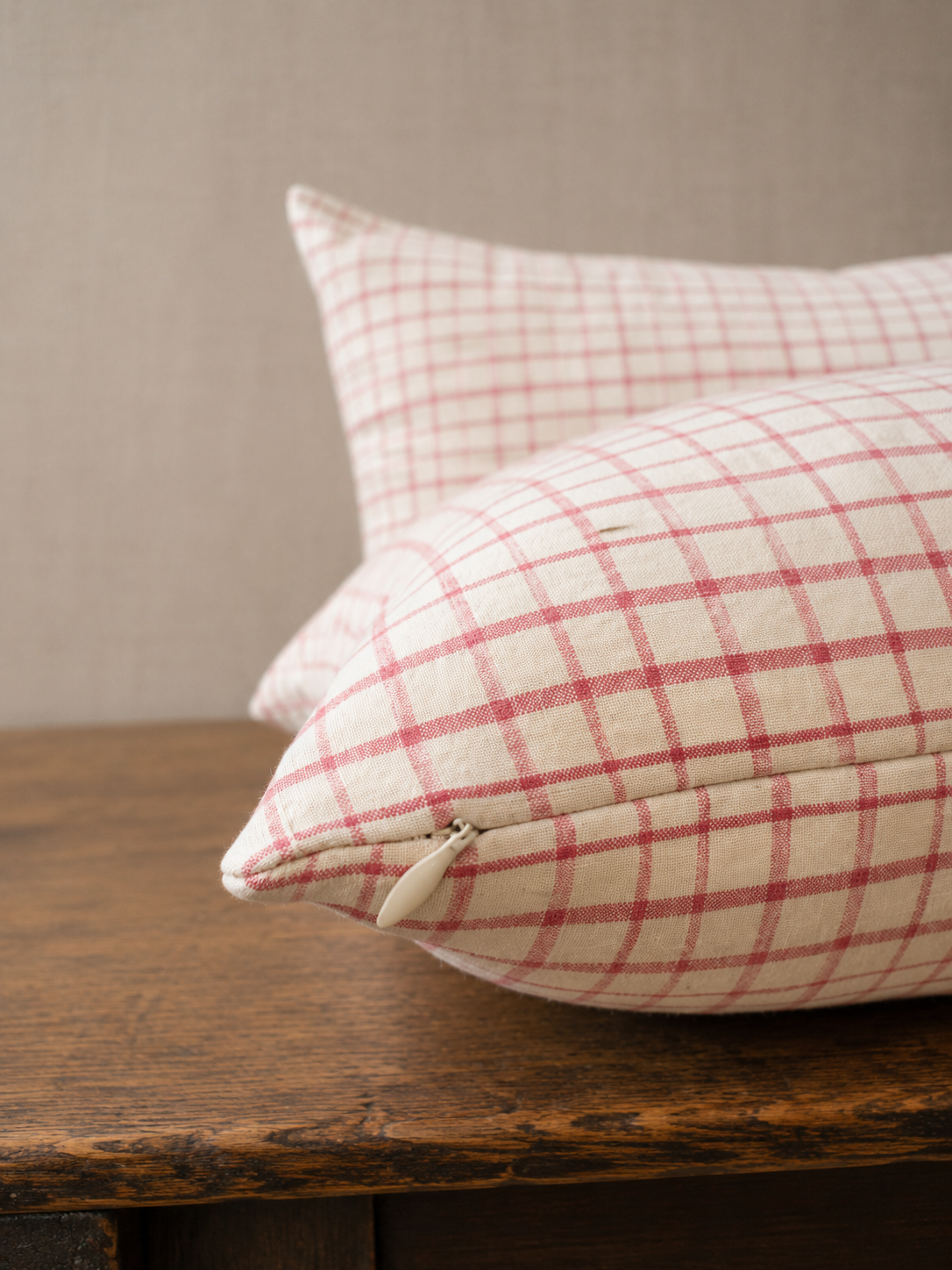 Two plaid pillows on a wooden surface with a neutral background