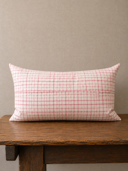 Checkered pillow on a wooden bench against a beige wall