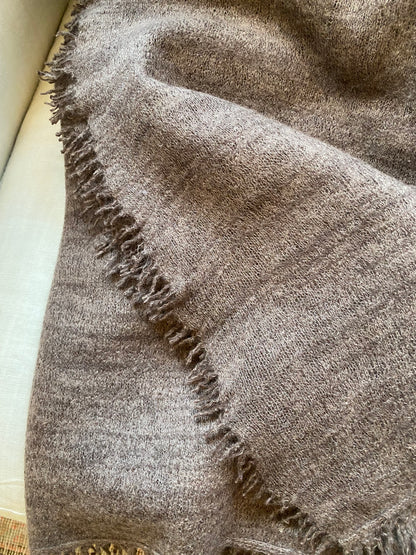 Brown textured blanket with frayed edges on a light background