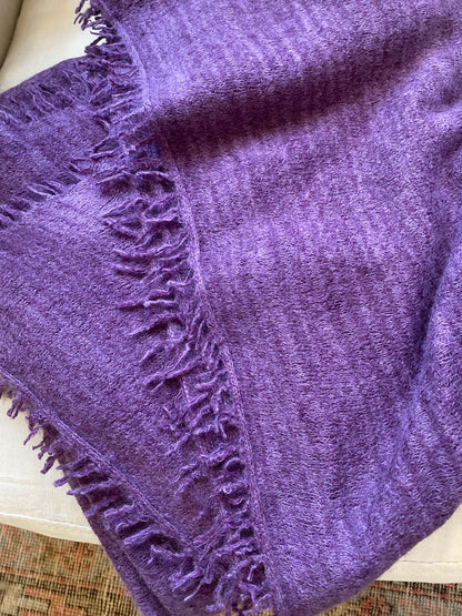 Purple blanket with textured edge on a white surface