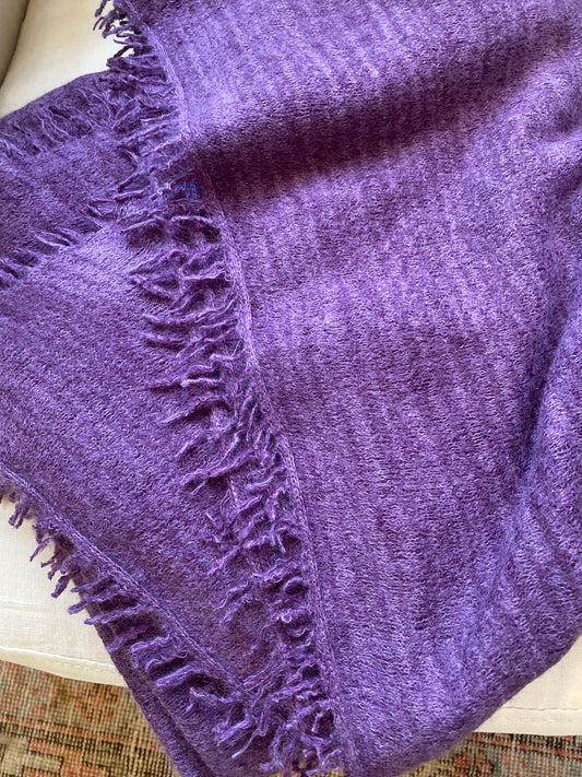 Purple blanket with textured edge on a white surface