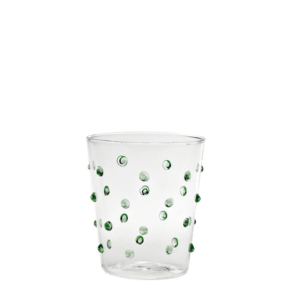 Clear glass tumbler with green dots on a white background