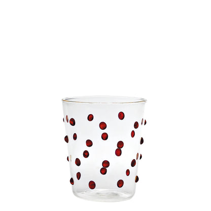 Clear glass tumbler with red polka dots on a white background