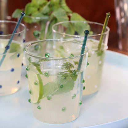 Three glasses of lemonade with lime slices and mint leaves on a white surface.