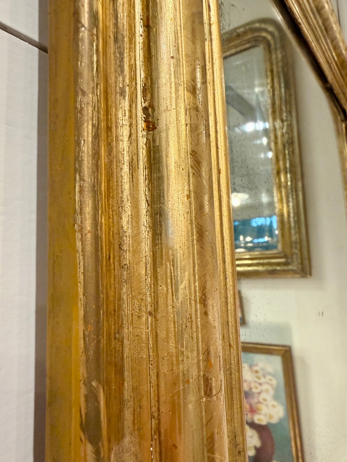 Close-up of a gold-framed mirror with visible markings highlighting age and beauty