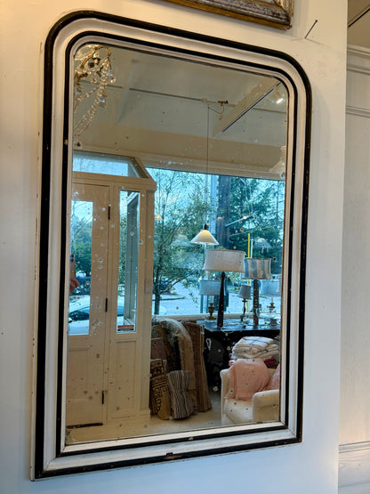 Decorative mirror with black frame reflecting a room interior.