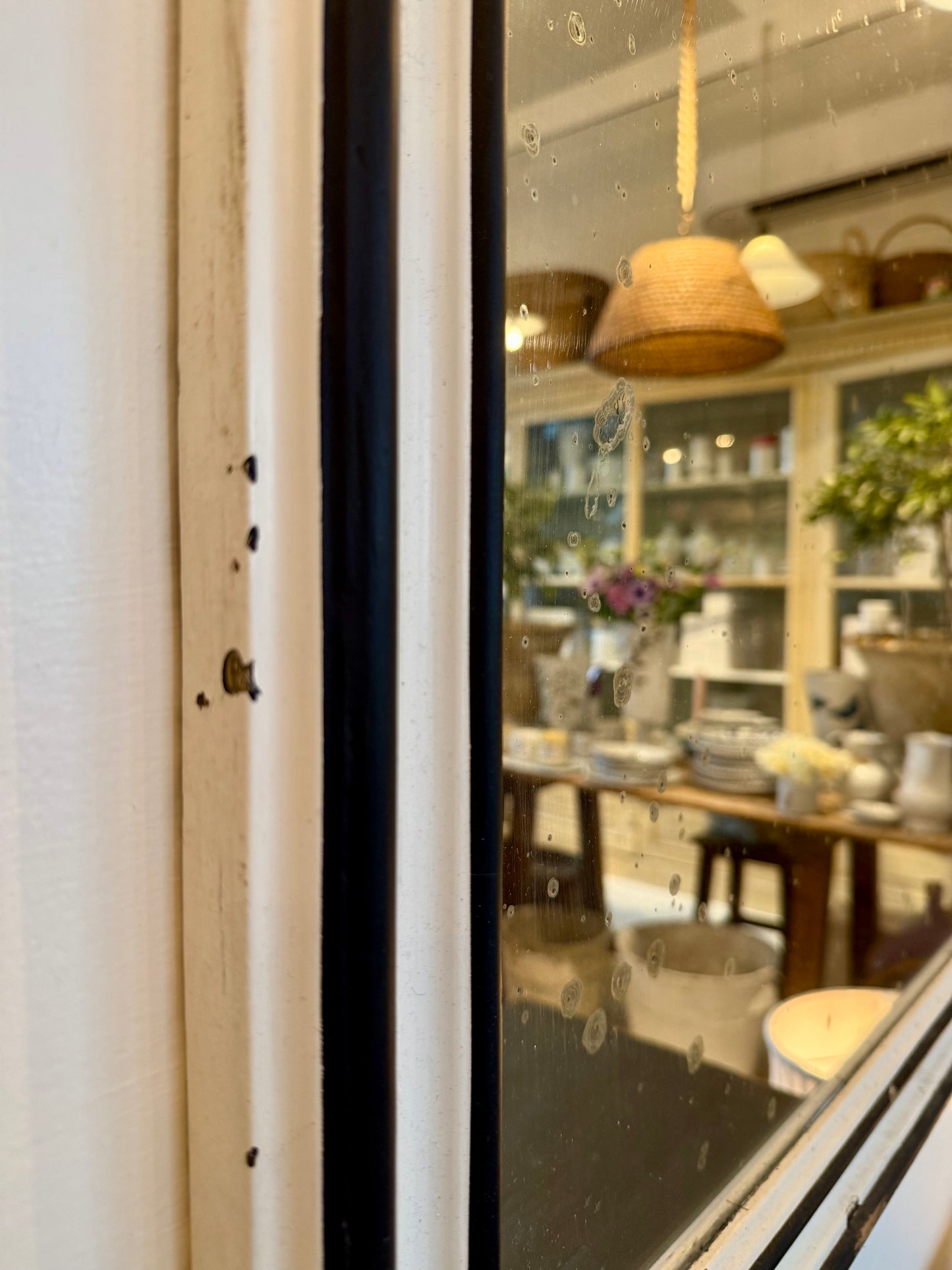 View through a vintage mirror into the red ticking store with various items on display.