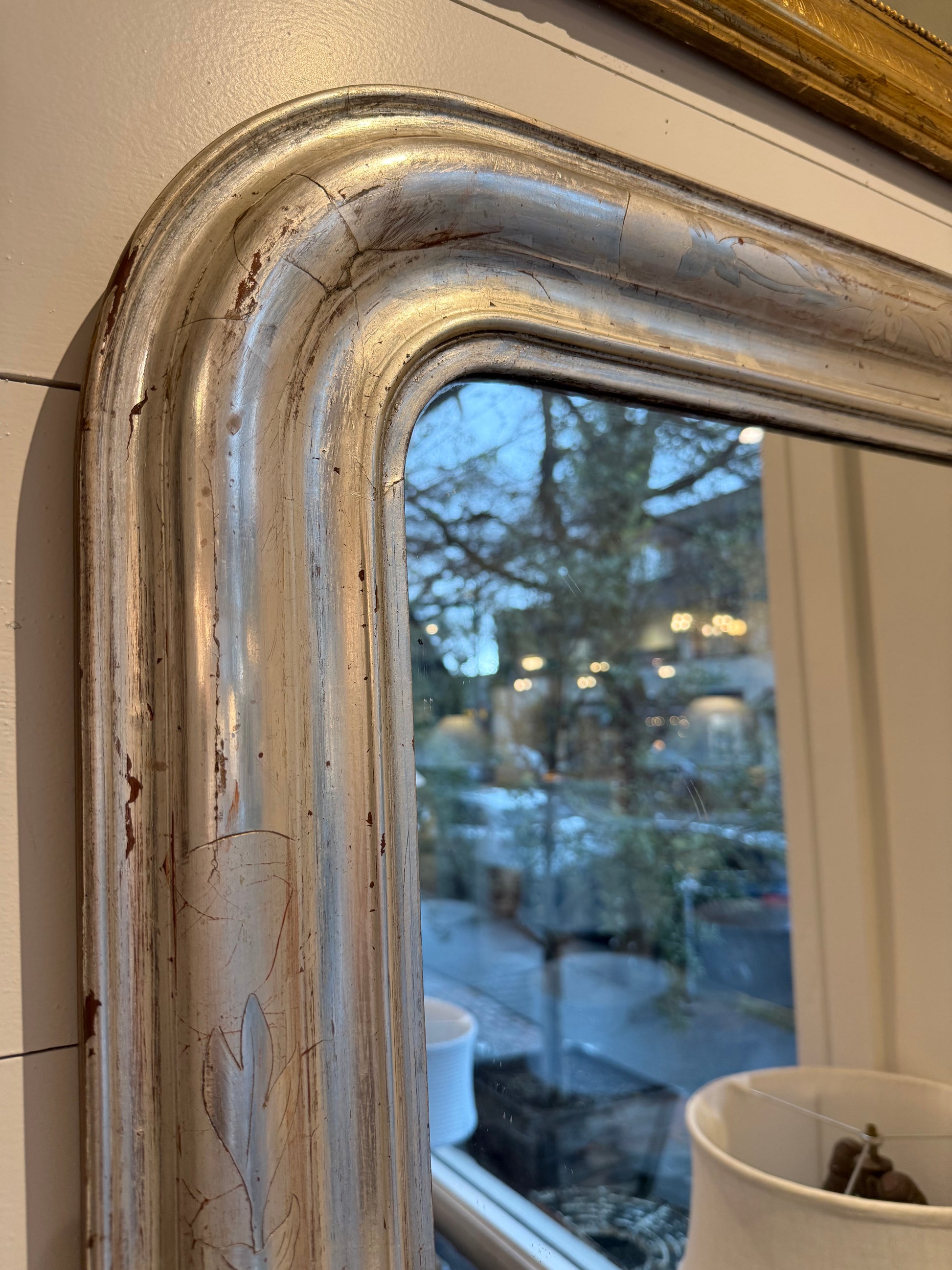 Close-up of a vintage mirror with reflective glass showing blurred outdoor scene