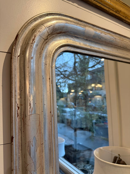 Close-up of a vintage mirror with reflective glass showing blurred outdoor scene