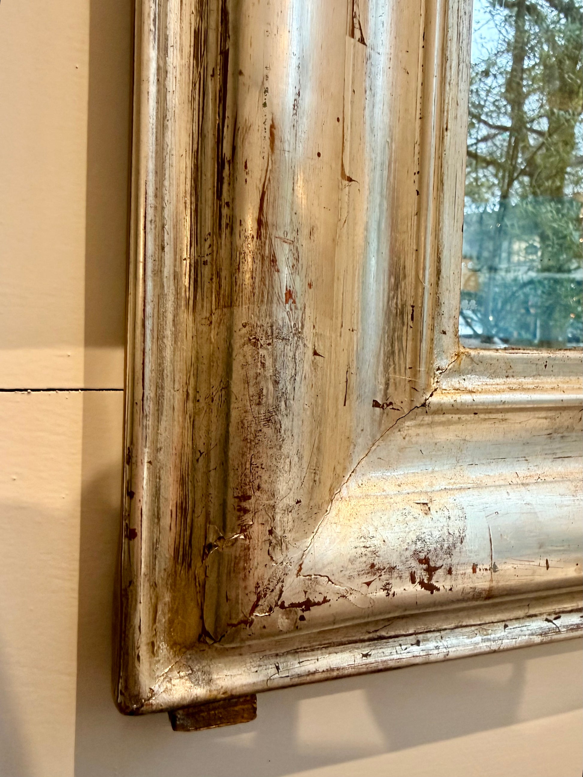 Close-up of a weathered wooden mirror with peeling paint.