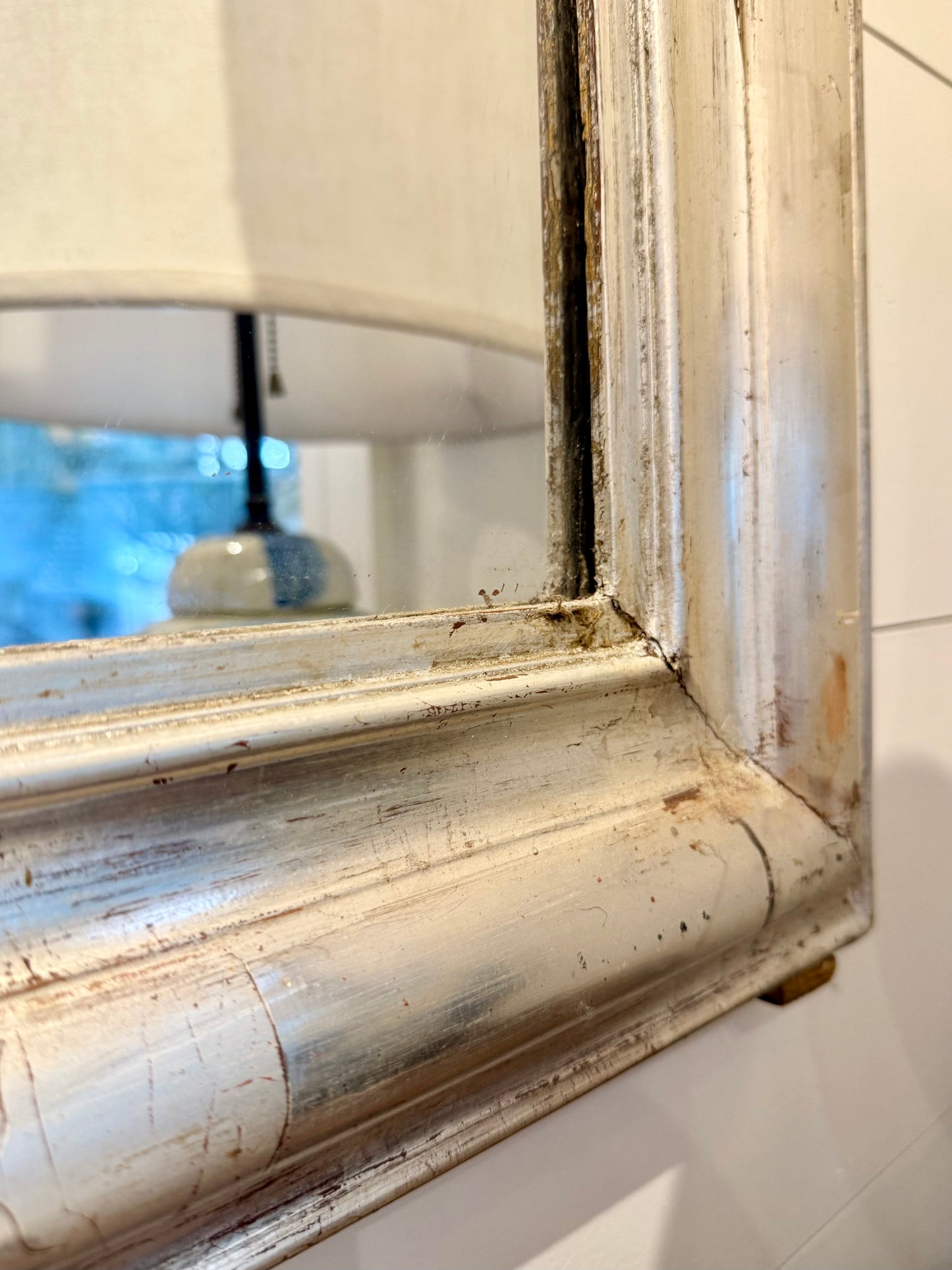 Close-up of a vintage mirror with visible wear and tear, including cracks and discoloration adding to its history and beauty. 