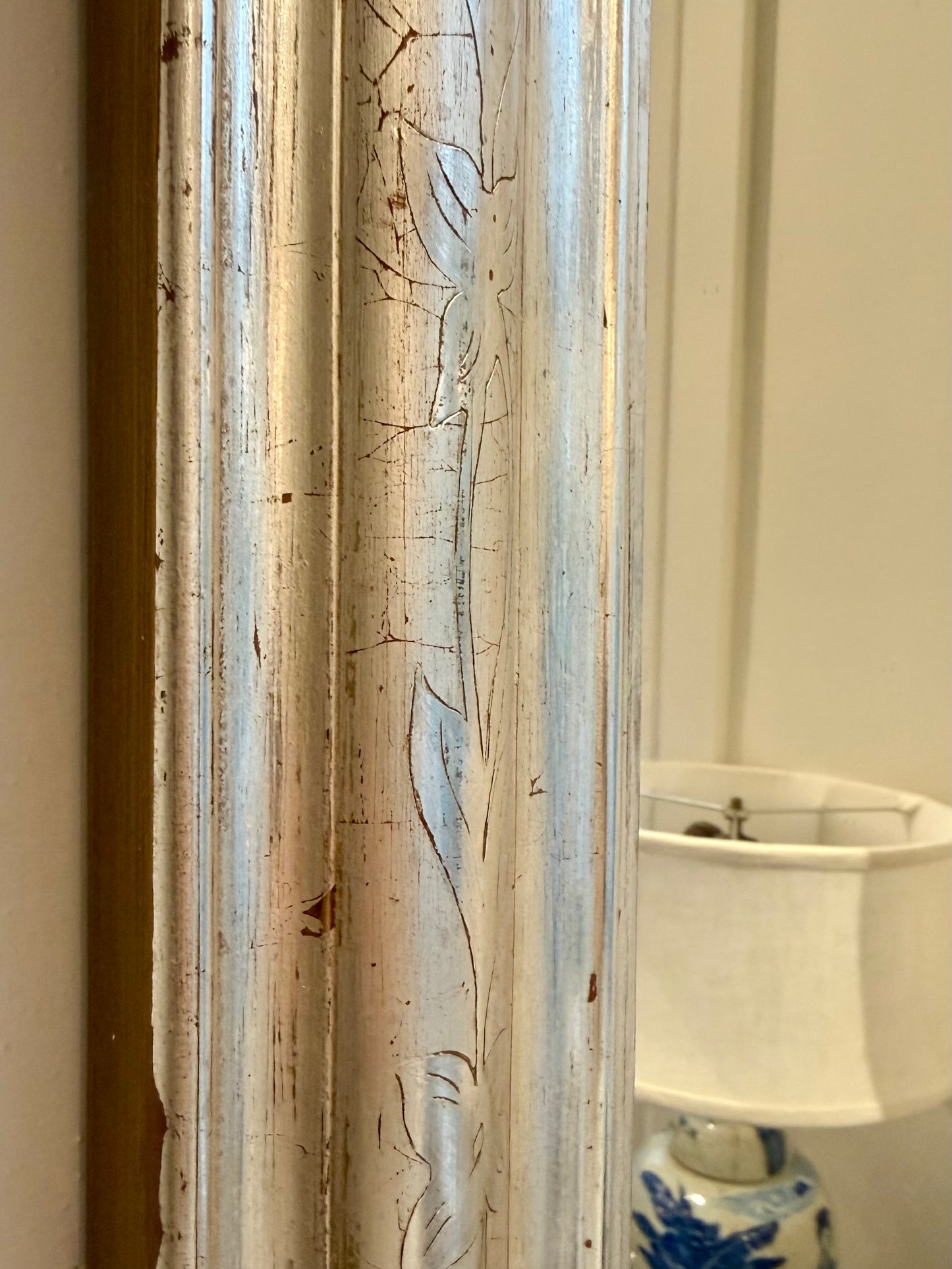 Upclose image of a decorative vintage mirror with a wooden frame and etched design.
