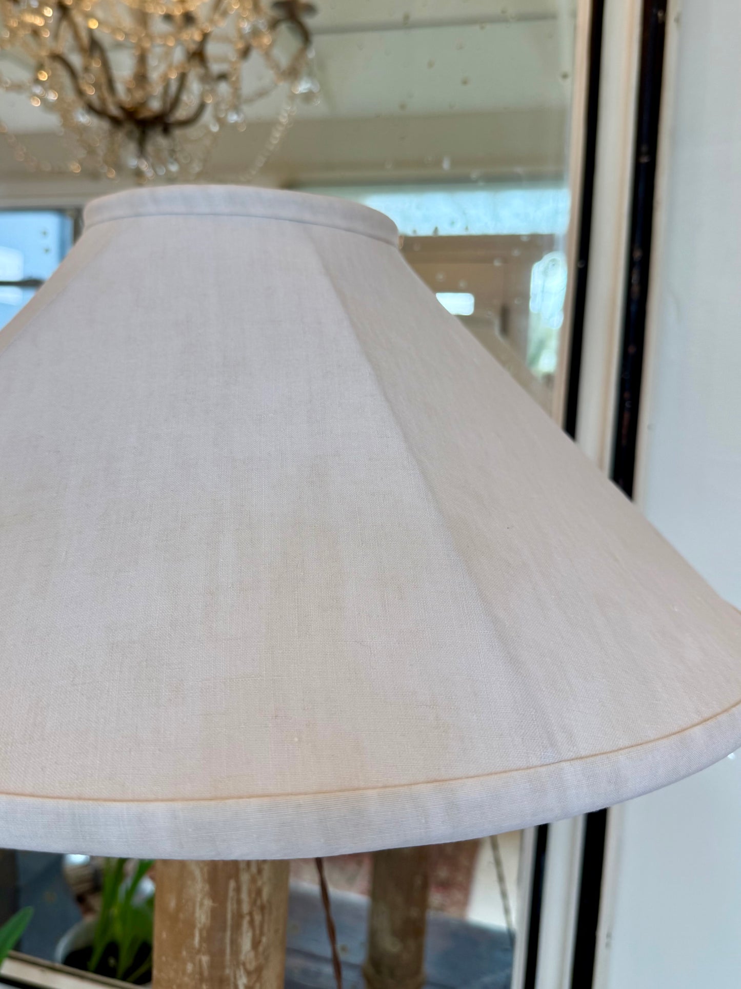Close-up of an off-white lampshade with a mirror in the background. 