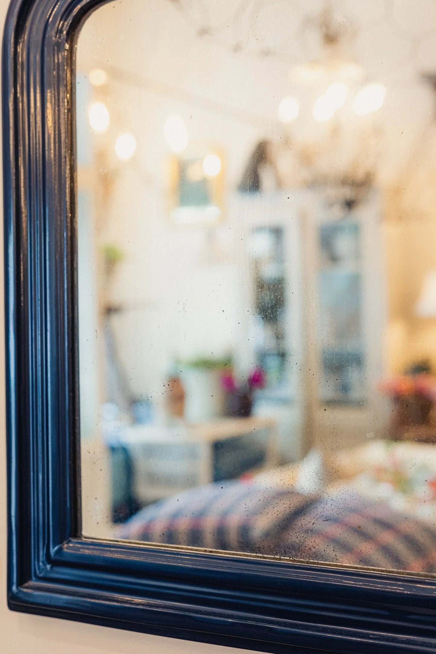 Decorative mirror with a black frame reflecting an interior setting.