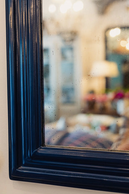 Close-up of a blue-framed mirror with a blurred interior background