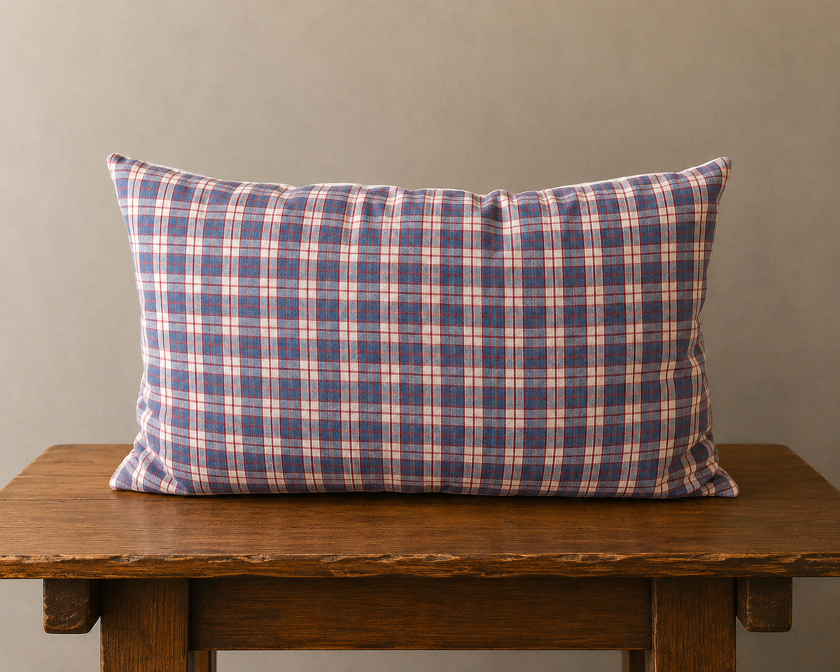 Plaid pillow on a wooden table against a plain wall