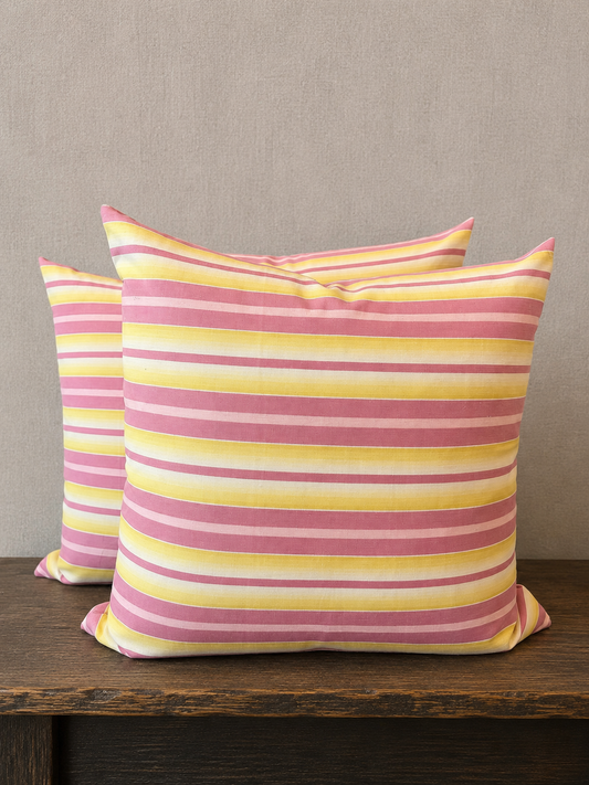 Two striped pillows with pink and yellow pattern on a wooden surface.