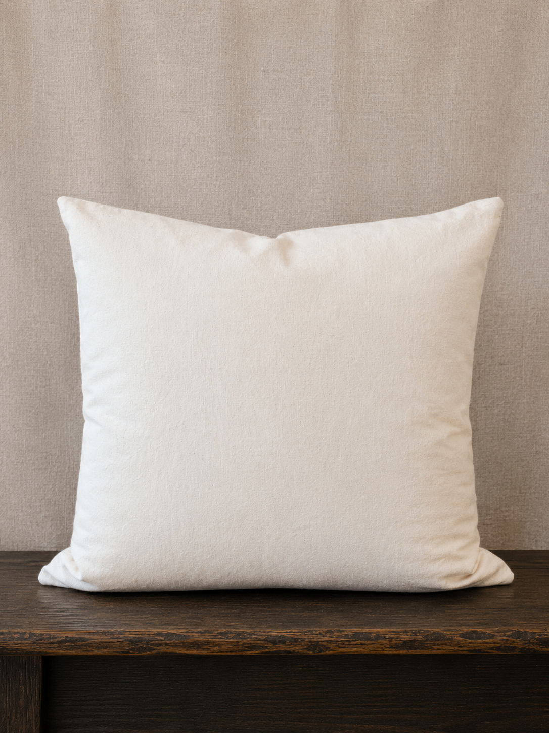 The back of the pillow on a wooden surface with a beige wall background