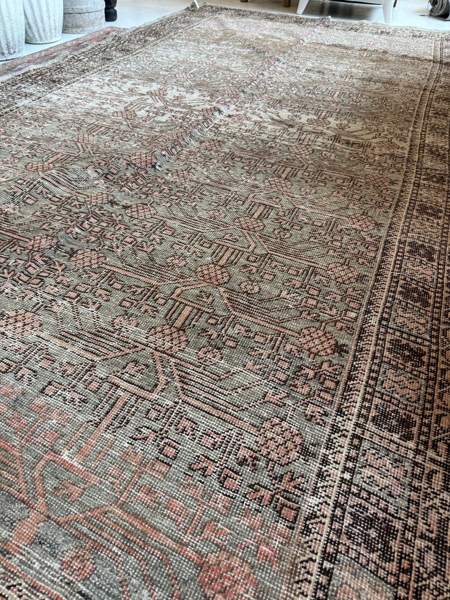 Detailed view of a vintage Khotan rug in wool, showing muted sage and blush tones with patterning.