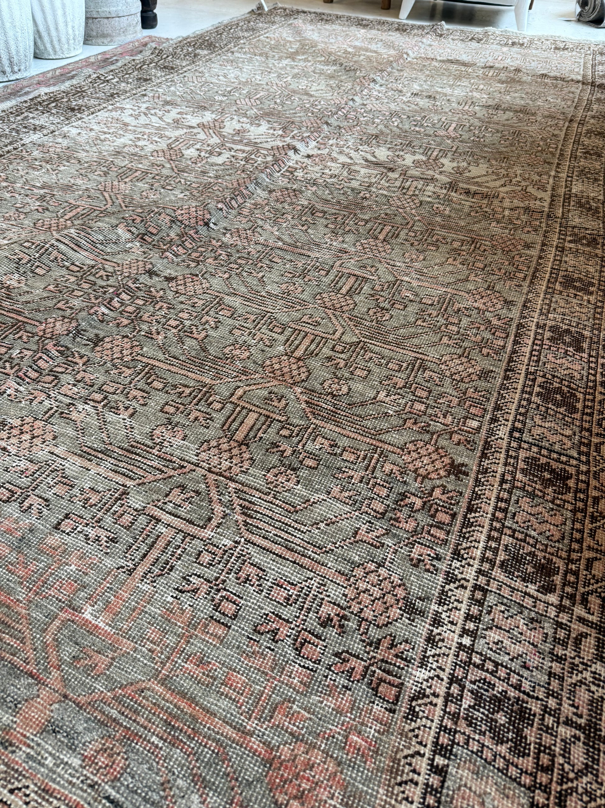 Detailed view of a vintage Khotan rug in wool, showing muted sage and blush tones with patterning.