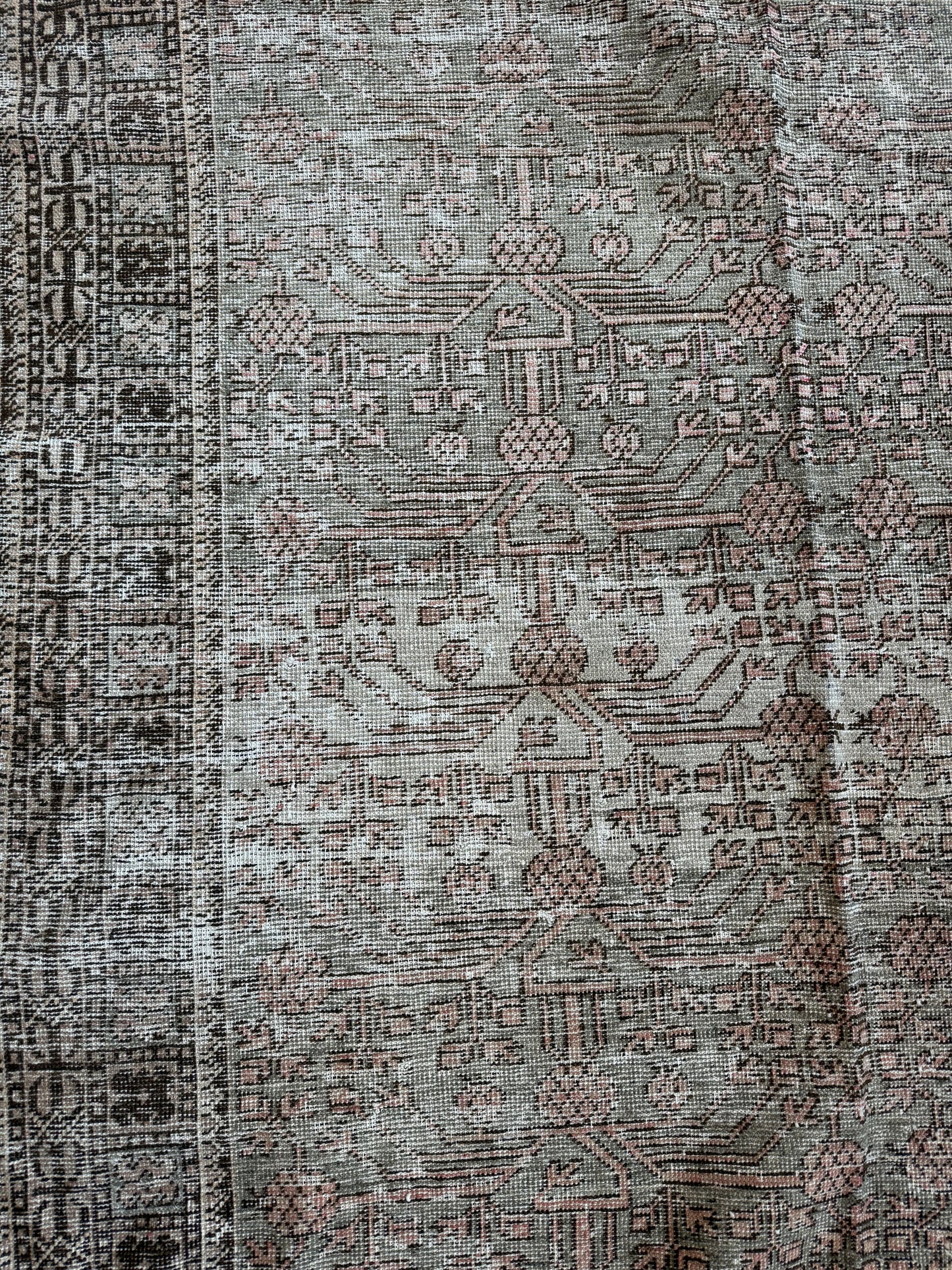 Close-up of a vintage Khotan wool rug featuring muted sage, blush, and brown tones with soft texture.
