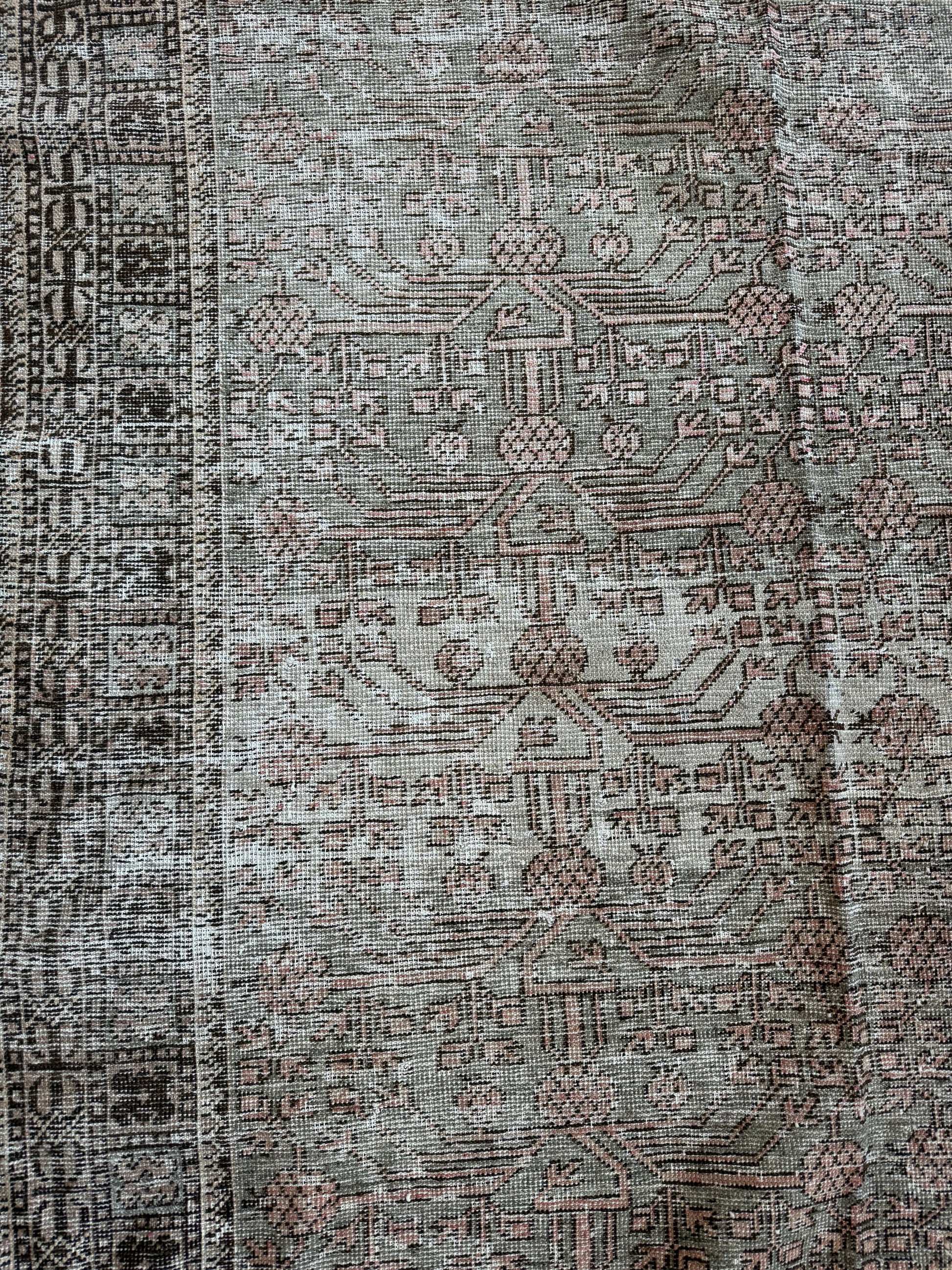 Close-up of a vintage Khotan wool rug featuring muted sage, blush, and brown tones with soft texture.