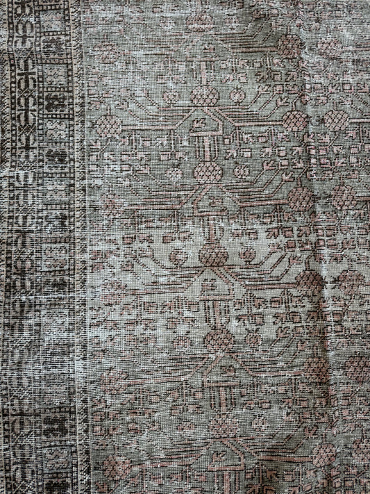 Close-up of a vintage Khotan wool rug featuring muted sage, blush, and brown tones with soft texture.