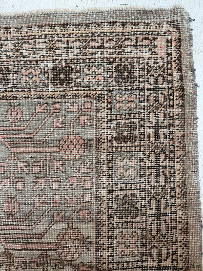 Close-up of vintage Khotan rug with sage, blush, and brown tones highlighting pattern. 