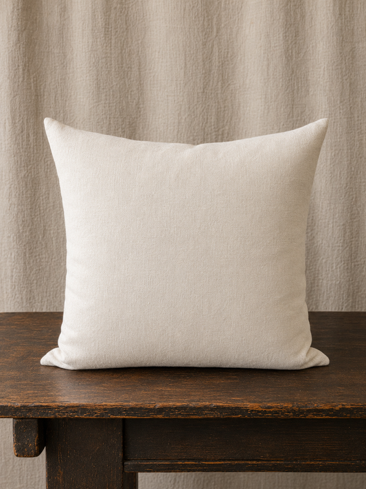 Back of pillow in beige on a wooden surface with a neutral background