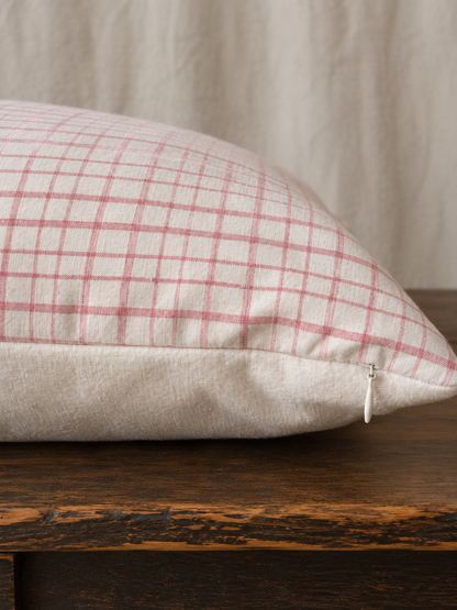Plaid pillow on a wooden surface with a neutral background