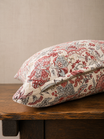 Decorative pillow with floral pattern on a wooden surface against a beige wall