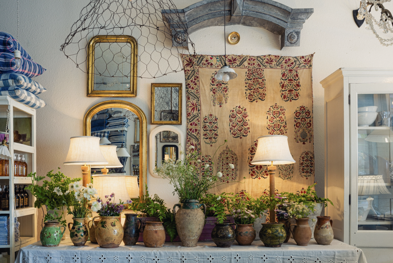 Decorative interior with mirrors, plants, and a tapestry on a wall.
