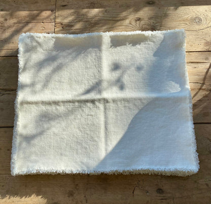 White Maya linen placemat on a wooden surface