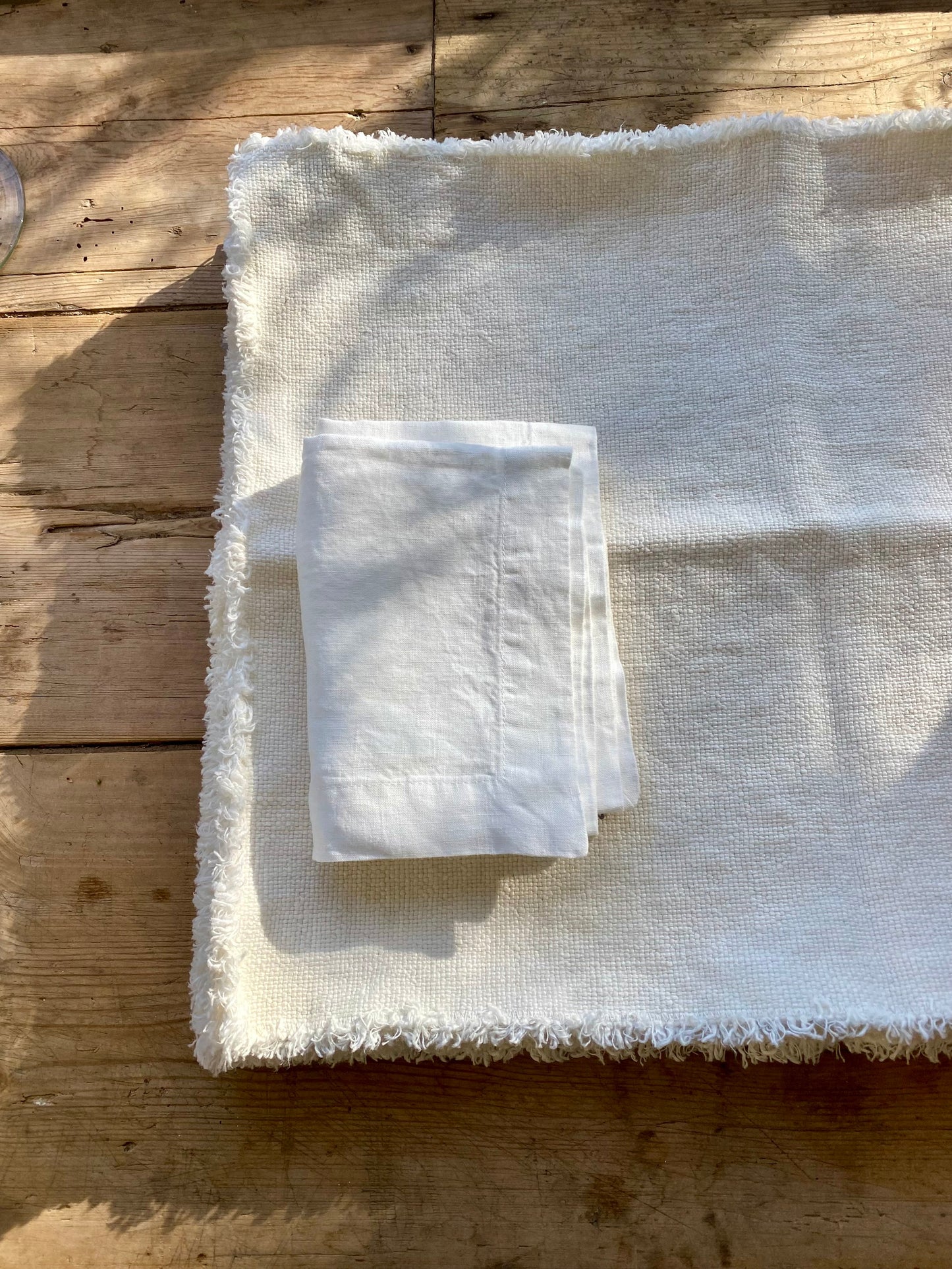 Folded white napkin on stack of Maya linen placemats