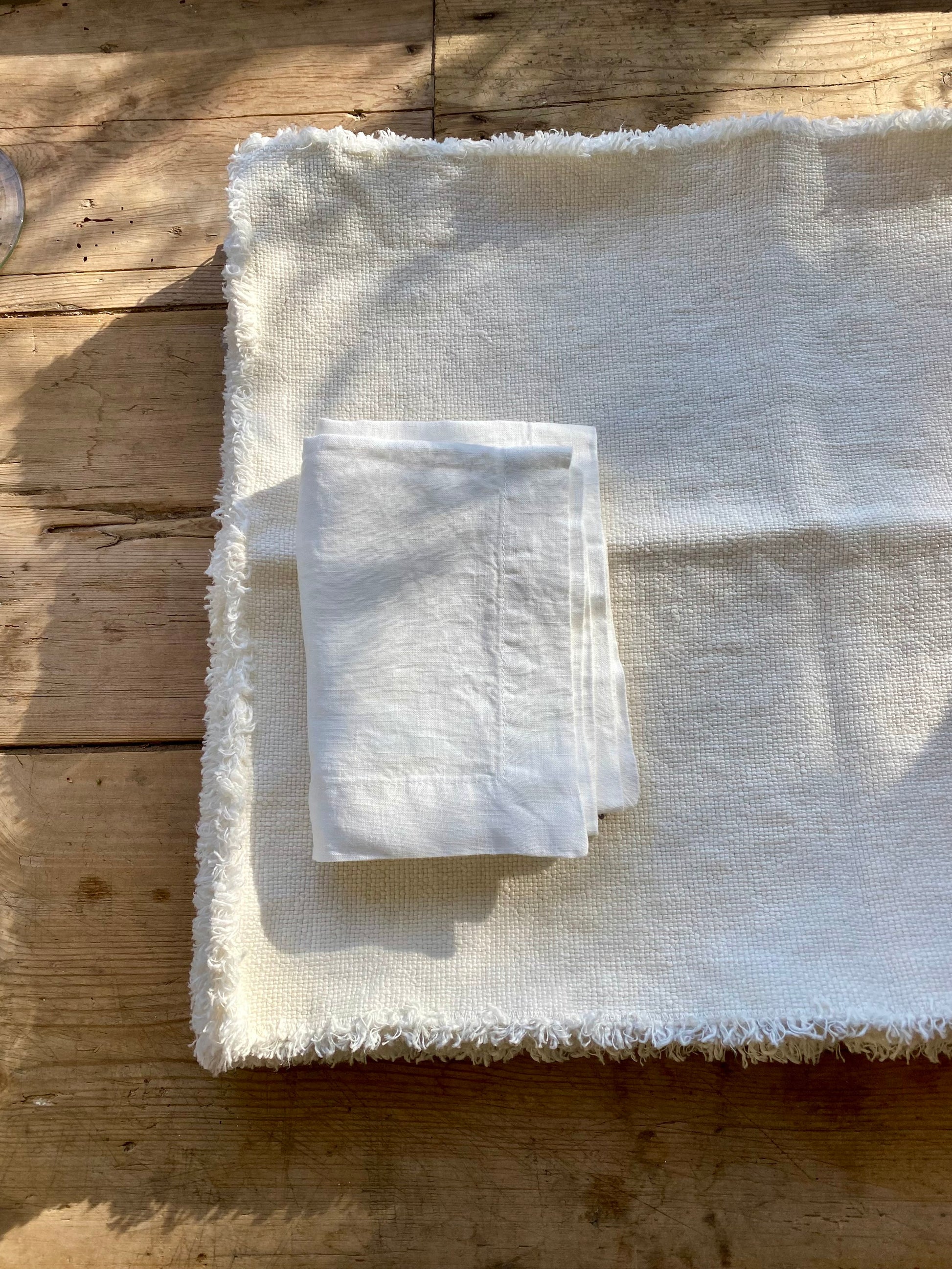 Folded white napkin on stack of Maya linen placemats